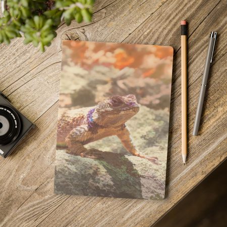 Val Weston's Gila Lagarto artwork on a softcover journal laying on a wooden tabletop.
