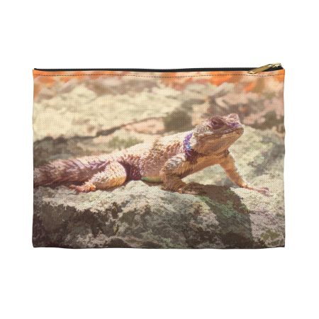 Close-up of a zipppered fabric pouch with a desert landscape print and an orange sky design on the top edge.